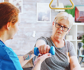 Older woman exercising with assistance from a physical therapist.