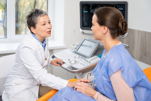 Picture of female doctor speaking with a female patient in an exam room.